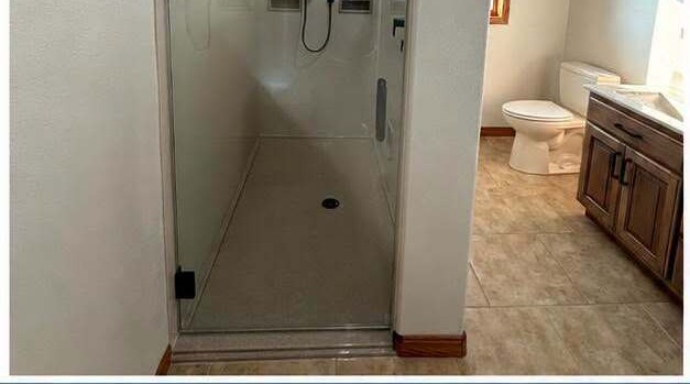 After: the same corner opened up into a long walk-in shower behind glass
