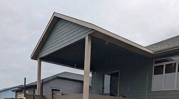 A covered structure with a finished roof, siding and wrapped posts