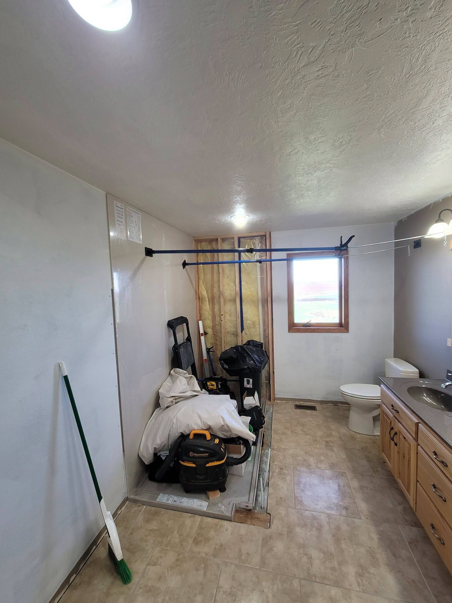 Demo day in a bathroom we are gutting: plastic sheeting, a shop vac and the fixtures stripped back