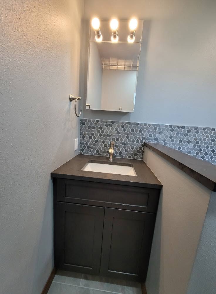 We finished this small bath with a dark vanity and a hex mosaic backsplash.